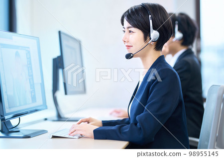 A female operator who wears a headset in the office and responds A female operator who wears a headset in the office and responds 98955145