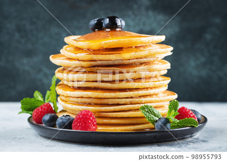 Delicious pancakes, with fresh blueberries, raspberry and maple syrup or honey on a dark background 98955793