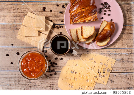 The idea of a delicious breakfast for the whole family. Wicker bun, cheese, apricot jam, waffles and aromatic black coffee. Layout The idea of a delicious breakfast for the whole family. Wicker bun, cheese, apricot jam, waffles and aromatic black coffee. Layout 98955898