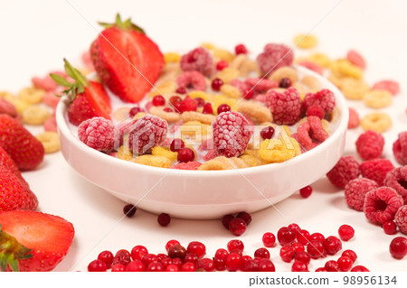 Corn rings with milk in a plate with berries and fruits, side view on a white background. The concept of quick breakfast cereals Corn rings with milk in a plate with berries and fruits, side view on a white background. The concept of quick breakfast cereals 98956134