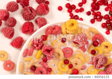 Corn rings with milk in a plate with berries and fruits, viewed from above on a white background. The concept of quick breakfast cereals Corn rings with milk in a plate with berries and fruits, viewed from above on a white background. The concept of quick breakfast cereals 98956135
