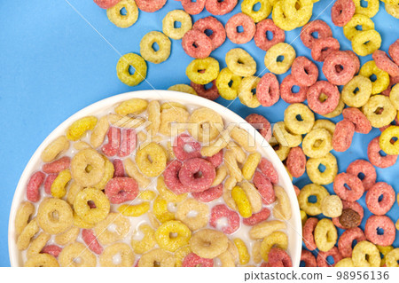 Corn rings drenched in milk in a plate on a light blue background, viewed from above. The concept of cereal quick breakfasts. Corn rings drenched in milk in a plate on a light blue background, viewed from above. The concept of cereal quick breakfasts. 98956136