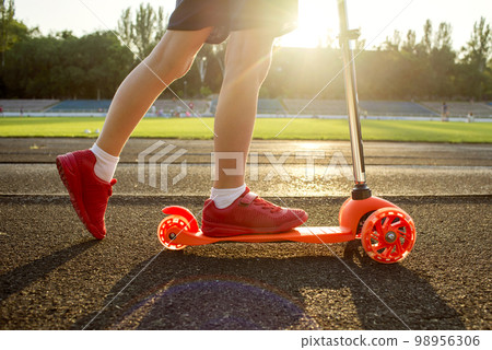 A child is riding scooter. Kid on colorful kick scooter 98956306