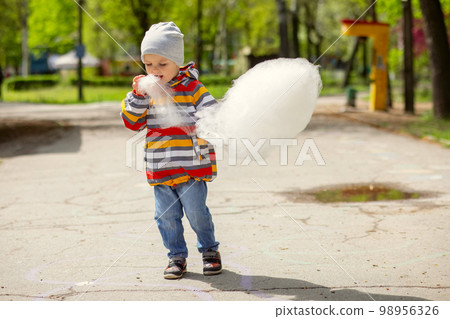 Child boy in an amusement park eats cotton candy Child boy in an amusement park eats cotton candy 98956326