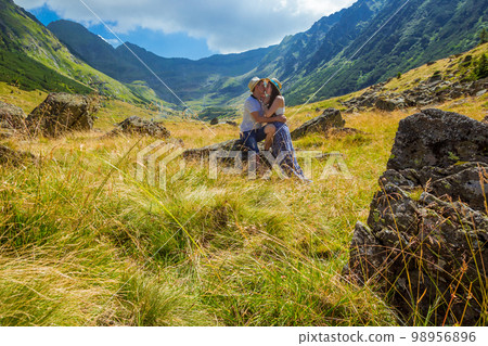 young couple kissing on a rock in front of romanian mountains 98956896