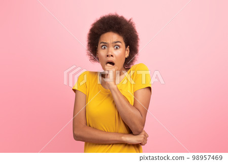 Frightened young black curly lady with open mouth scared and looking at camera Frightened young black curly lady with open mouth scared and looking at camera 98957469
