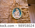 Traditional religious catholic bas-relief od Virgin Mary with baby Jesus near the building entrance in Mdina, Malta. 98958024