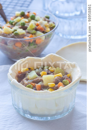 Making individual beef pot pies, step 4 put in filling, horizontal Making individual beef pot pies, step 4 put in filling, horizontal 98958861