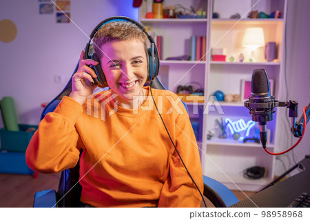 Young short haircut woman gamer playing video games wearing headphones smiling looking at camera Young short haircut woman gamer playing video games wearing headphones smiling looking at camera 98958968