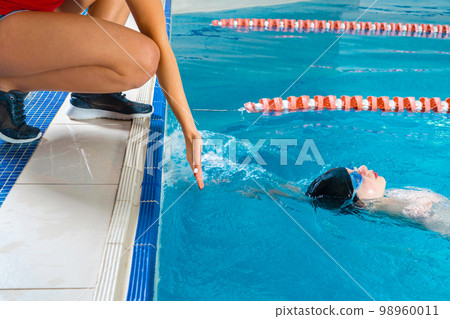 Female Coach In Water Giving preteen boy swimming Lesson In Indoor Pool 98960011