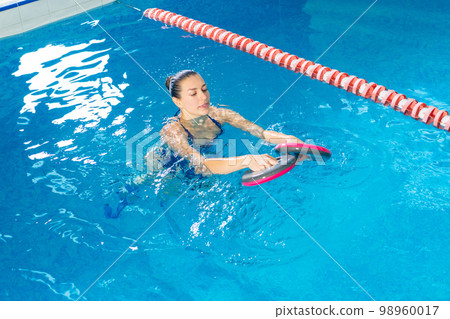 Young woman doing water aerobics in indoor pool, sporting concept Young woman doing water aerobics in indoor pool, sporting concept 98960017