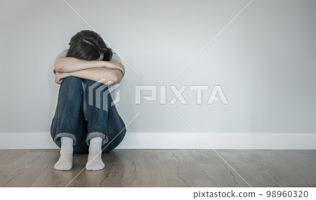 Sad woman sitting on a floor alone in empty room, despair and lonely concept with copy space Sad woman sitting on a floor alone in empty room, despair and lonely concept with copy space 98960320