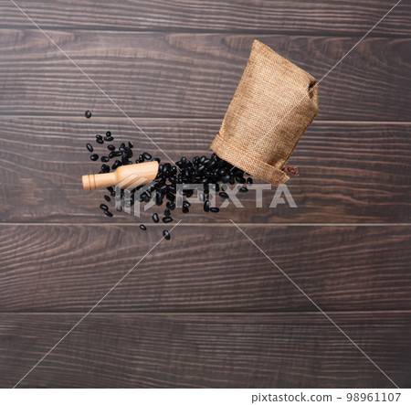Black Bean flying explosion in sack bag, black grain beans explode abstract cloud fly. Beautiful complete seed pea bean bag splash in air, food object design. Wooden background isolated freeze 98961107