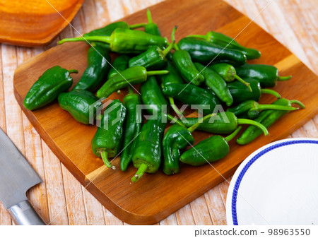 Lots of green peppers on wooden cutting board Lots of green peppers on wooden cutting board 98963550