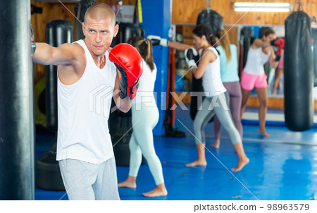 Man and women punching bags in gym 98963579
