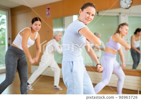 Active positive women of different ages performing dance aerobic elements during lesson in modern fitness gym 98963726