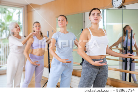 Female ballet instructor adjusting students form in dancing school 98963754