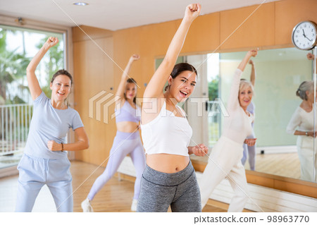 Emotional sportive female dancers of different ages in sportswear exercising new dance moves in fitness studio 98963770