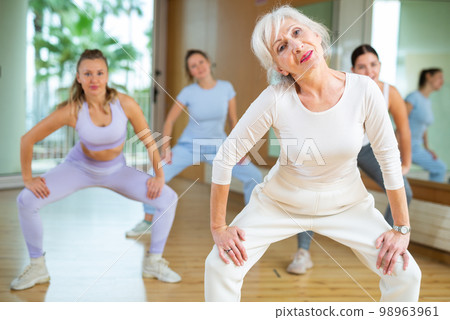 Dynamic elderly woman practicing aerobic dance in training hall 98963961