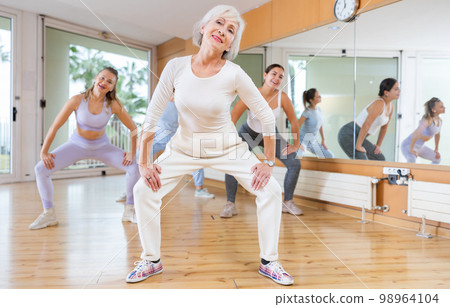 Dynamic elderly woman practicing aerobic dance in training hall 98964104