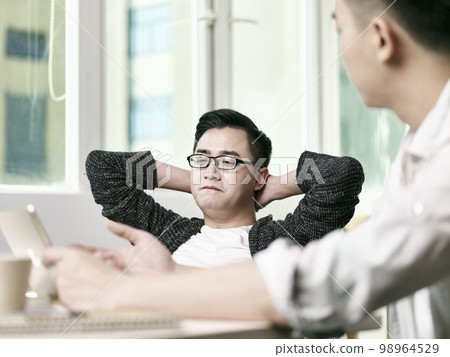 two young asian entrepreneurs discussing business in office using digital tablet 98964529