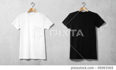 掛在衣架上的黑白 T 卹靠在混凝土牆上 98965068