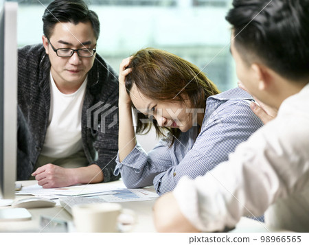 frustrated asian businesswoman getting comfort from colleagues while discussing business in office 98966565