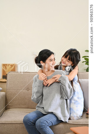 Lovely Asian mom and daughter playing and spending time together in their living room. Lovely Asian mom and daughter playing and spending time together in their living room. 98968376
