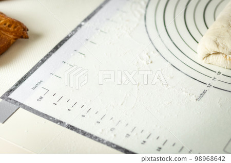 White silicone baking mat with centimeter and inch markings sprinkled with flour, copy space 98968642