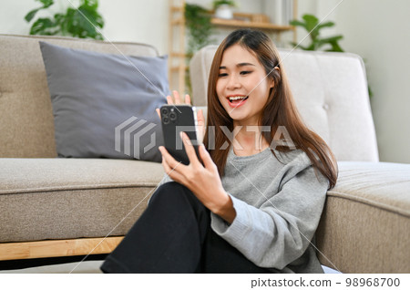 Attractive Asian female on her smartphone talking or video calling with her friends 98968700