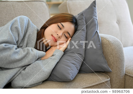 Relaxed young Asian female taking an afternoon nap on the sofa, fall asleep on couch Relaxed young Asian female taking an afternoon nap on the sofa, fall asleep on couch 98968706