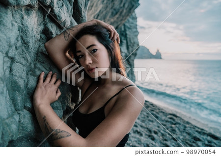 Portrait of cheerful female climber resting on a volcanic basalt 98970054
