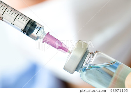 doctor's hand holds a syringe and a blue vaccine bottle at the hospital. Health and medical concepts. doctor's hand holds a syringe and a blue vaccine bottle at the hospital. Health and medical concepts. 98971195