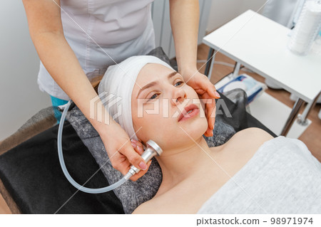 Woman in the beauty services. Masseur makes vacuum roller massage 98971974