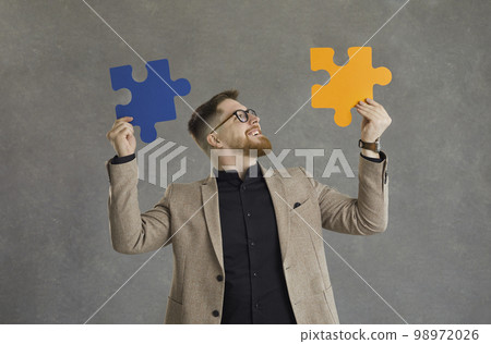 Man connecting pieces of jigsaw puzzle as metaphor for professional business solution 98972026
