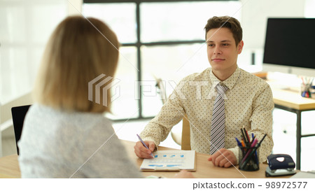 Businessman talking with partner at table in office 98972577