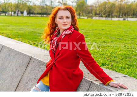 Outdoors fashion portrait young elegant woman in red coat and yellow sweater Outdoors fashion portrait young elegant woman in red coat and yellow sweater 98972822