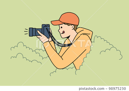Young man reporter hide in bushes make pictures 98975230