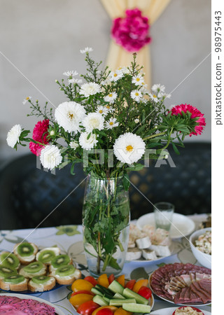 A bouquet of homemade asters in a glass vase in the decor of a country banquet A bouquet of homemade asters in a glass vase in the decor of a country banquet 98975443