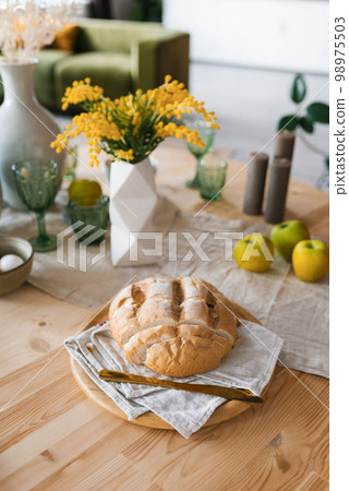 A loaf of fresh bread on the breakfast table, mimosa flowers in a vase A loaf of fresh bread on the breakfast table, mimosa flowers in a vase 98975503