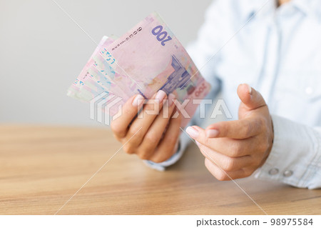 Woman holding Ukrainian 200 bill banknotes. Propose Ukrainian money. 98975584