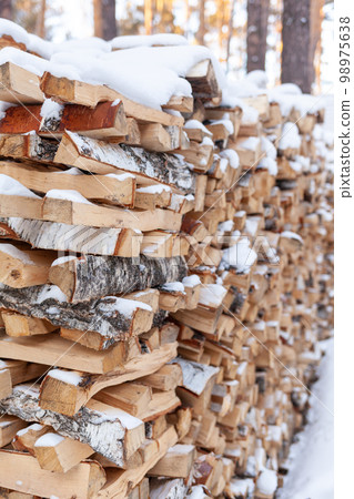 Stacked firewood covered with white snow, wood for kindling Stacked firewood covered with white snow, wood for kindling 98975638
