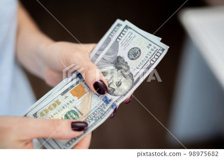 Close up female hand Counting and holding money us dollar. 98975682