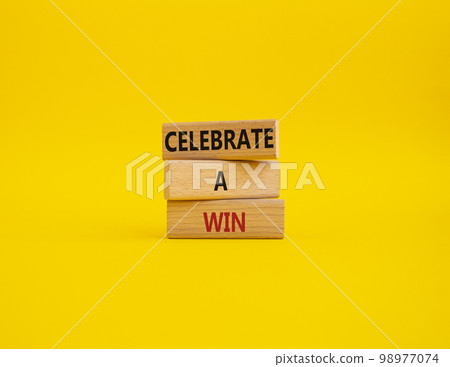 Celebrate a win symbol. Concept words Celebrate a win on wooden blocks. Beautiful yellow background. Business and Celebrate a win concept. Copy space. 98977074