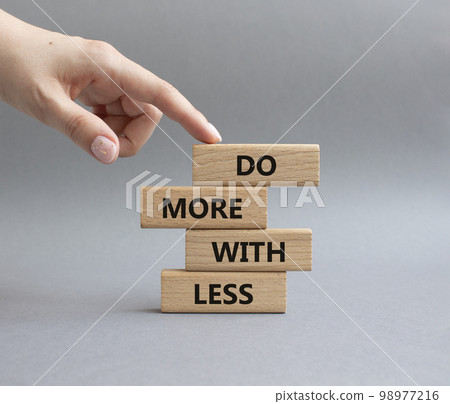 Do more with less symbol. Concept words Do more with less on wooden blocks. Beautiful grey background. Businessman hand. Business and Do more with less concept. Copy space. 98977216