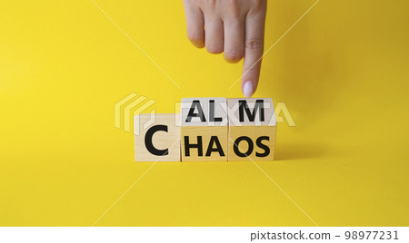 Calm vs chaos symbol. Businessman hand points at turned wooden cubes with words Chaos and Calm. Beautiful yellow background. Business and Calm vs chaos concept. Copy space. Calm vs chaos symbol. Businessman hand points at turned wooden cubes with words Chaos and Calm. Beautiful yellow background. Business and Calm vs chaos concept. Copy space. 98977231