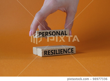 Personal resilience symbol. Wooden blocks with words Personal resilience. Businessman hand. Beautiful orange background. Business and Personal resilience concept. Copy space. 98977336
