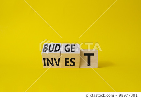 Budget or Invest symbol. Wooden cubes with words Invest and Budget. Beautiful yellow background. Business and Budget and Invest concept. Copy space 98977391