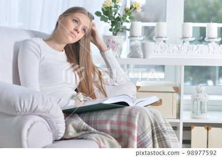 Young woman with a book in cozy armchair 98977592