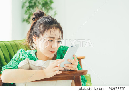 A woman lying on the sofa and looking at her smartphone A woman lying on the sofa and looking at her smartphone 98977761